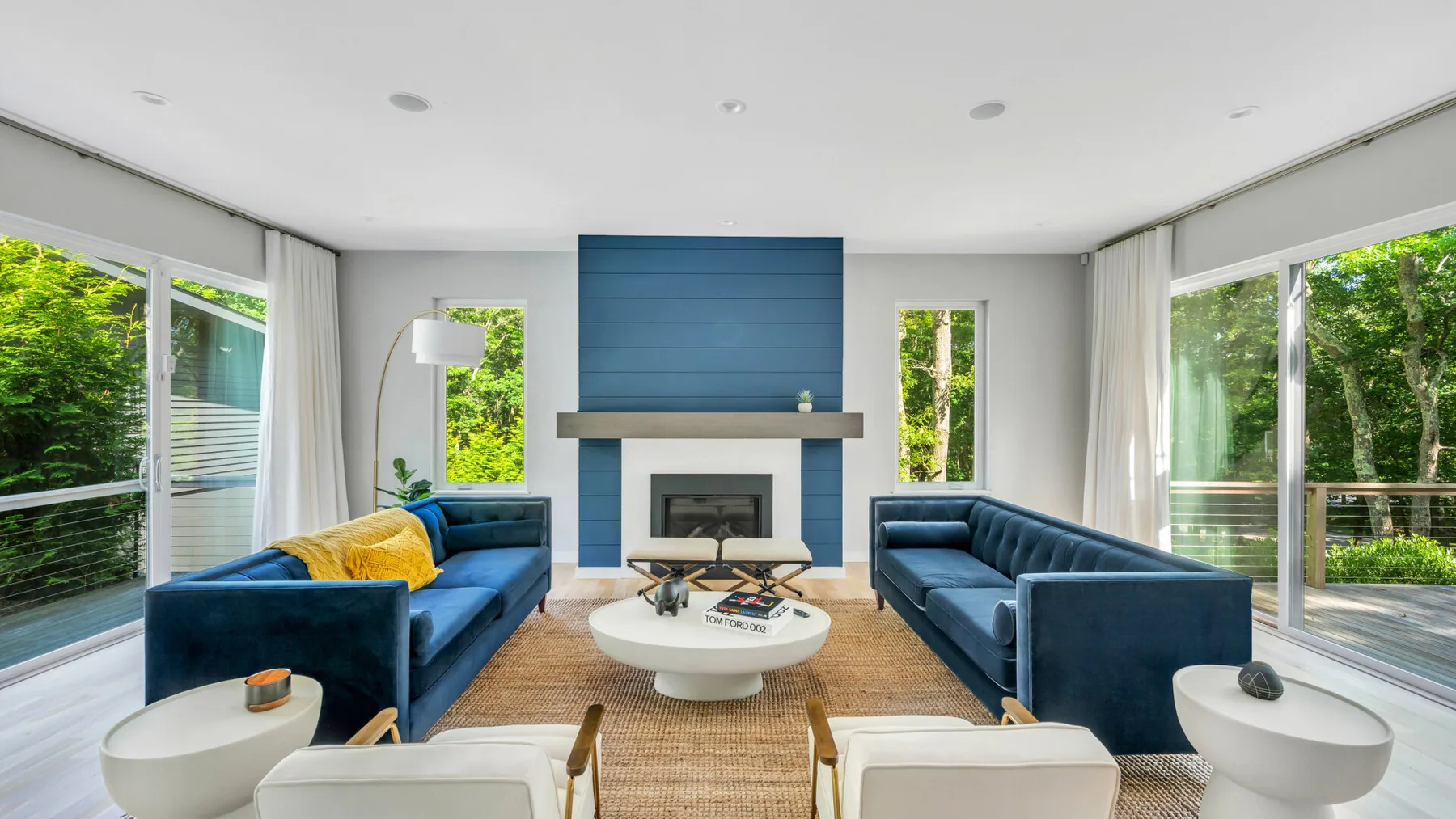 A bright living room with blue seating arranged around a coffee table and fireplace.