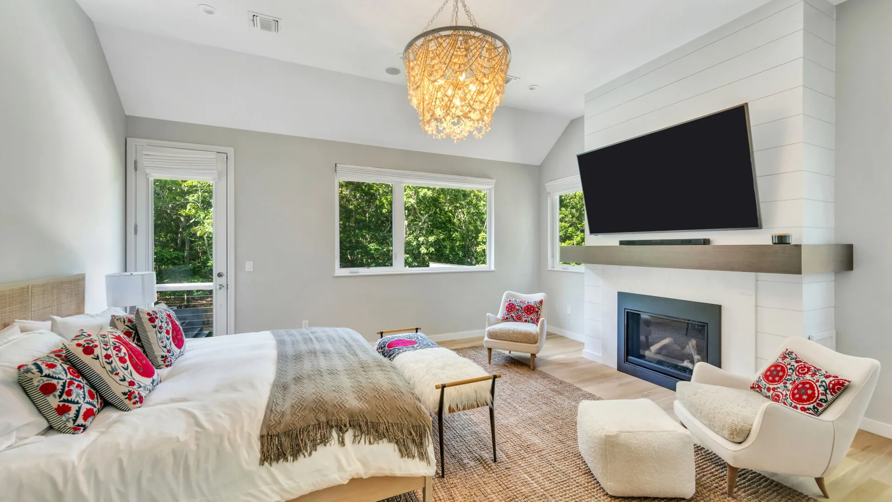 A bright living room with a bed, seating, and a wall-mounted television.