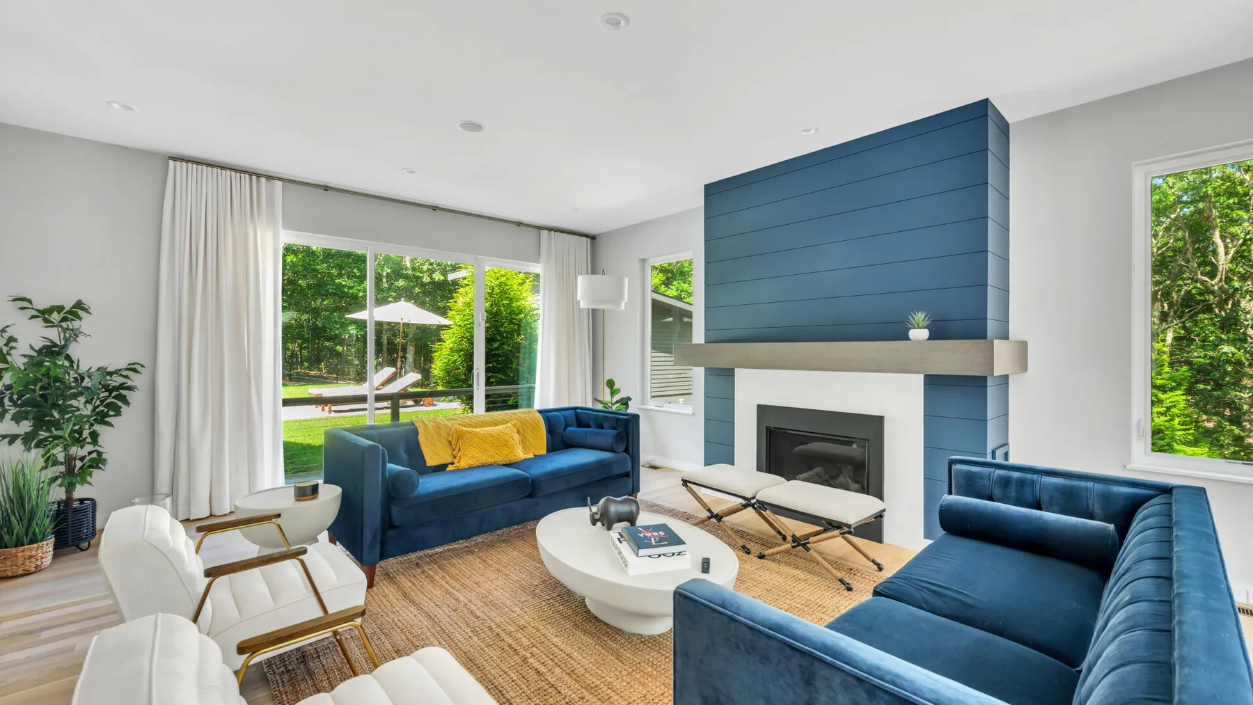 A living room with blue seating, a fireplace, and large windows.