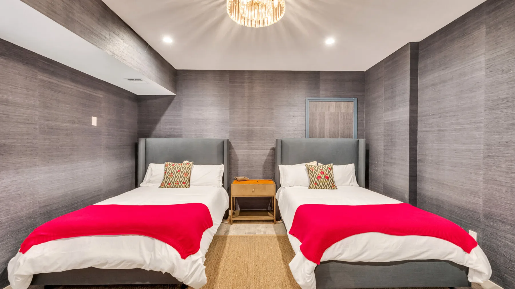 A bedroom with two single beds, each topped with a bright red blanket.