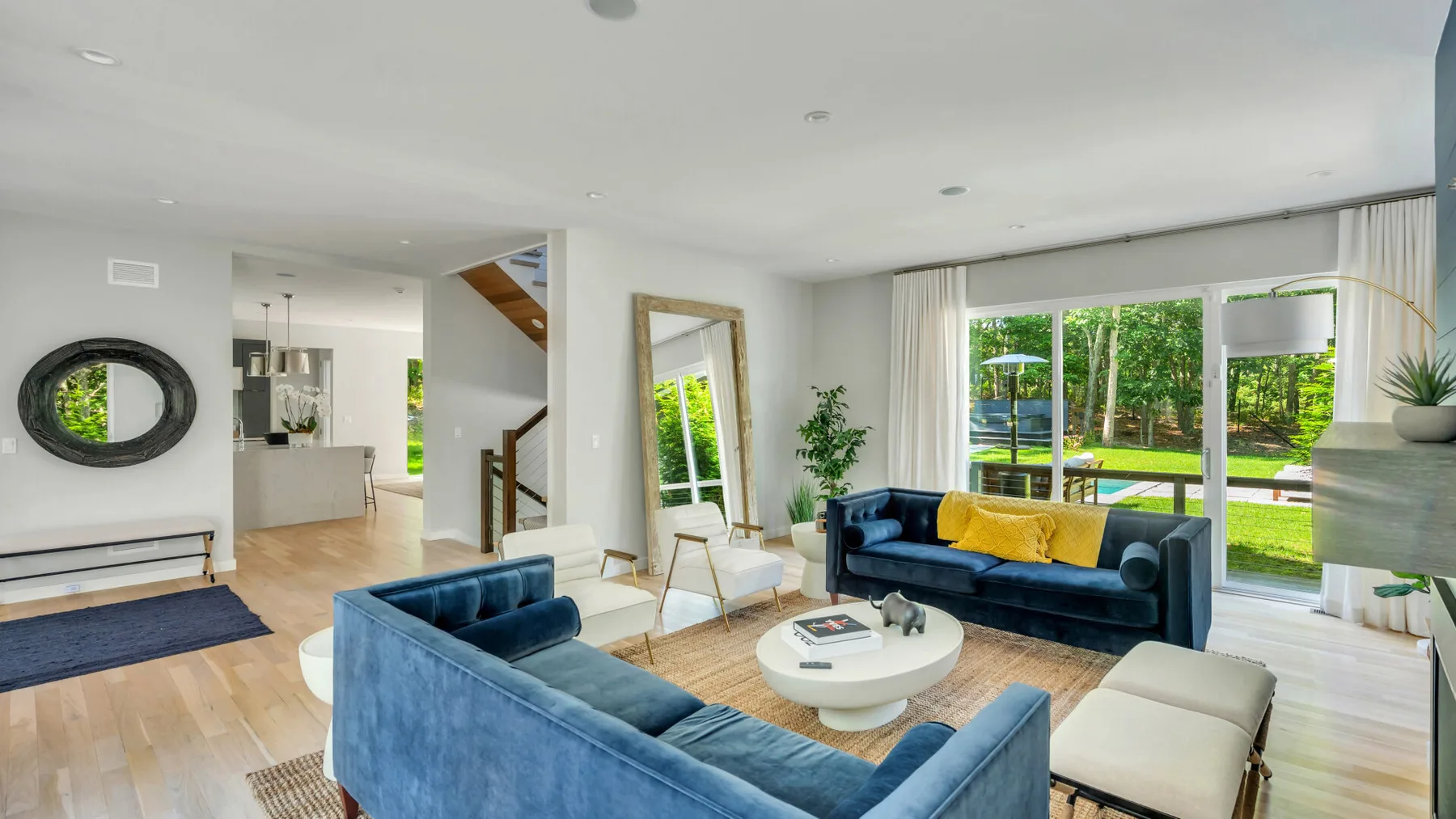 A bright living room with blue seating and large windows overlooking greenery.