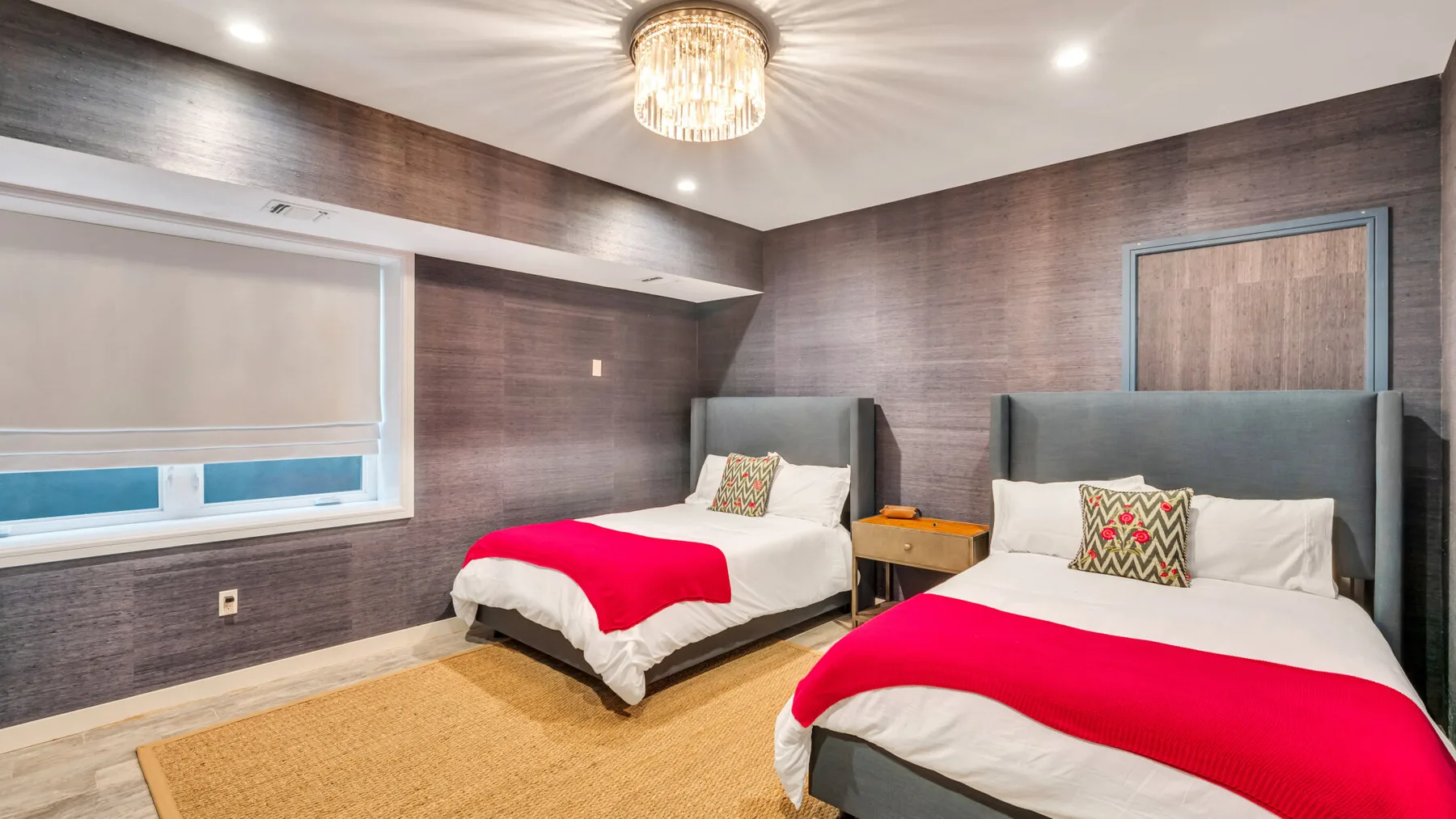 A bedroom with two beds, white bedding, and bright red blankets.