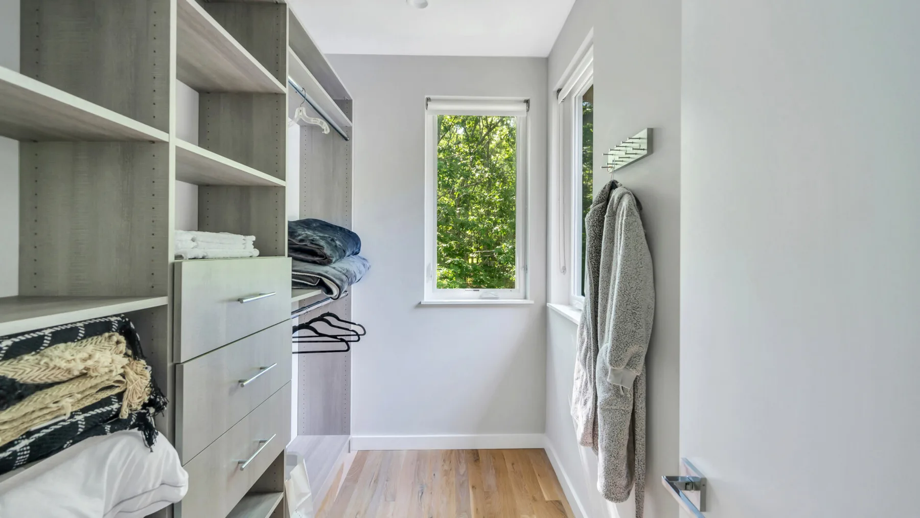 A walk-in closet with open shelving, drawers, and hanging clothes.