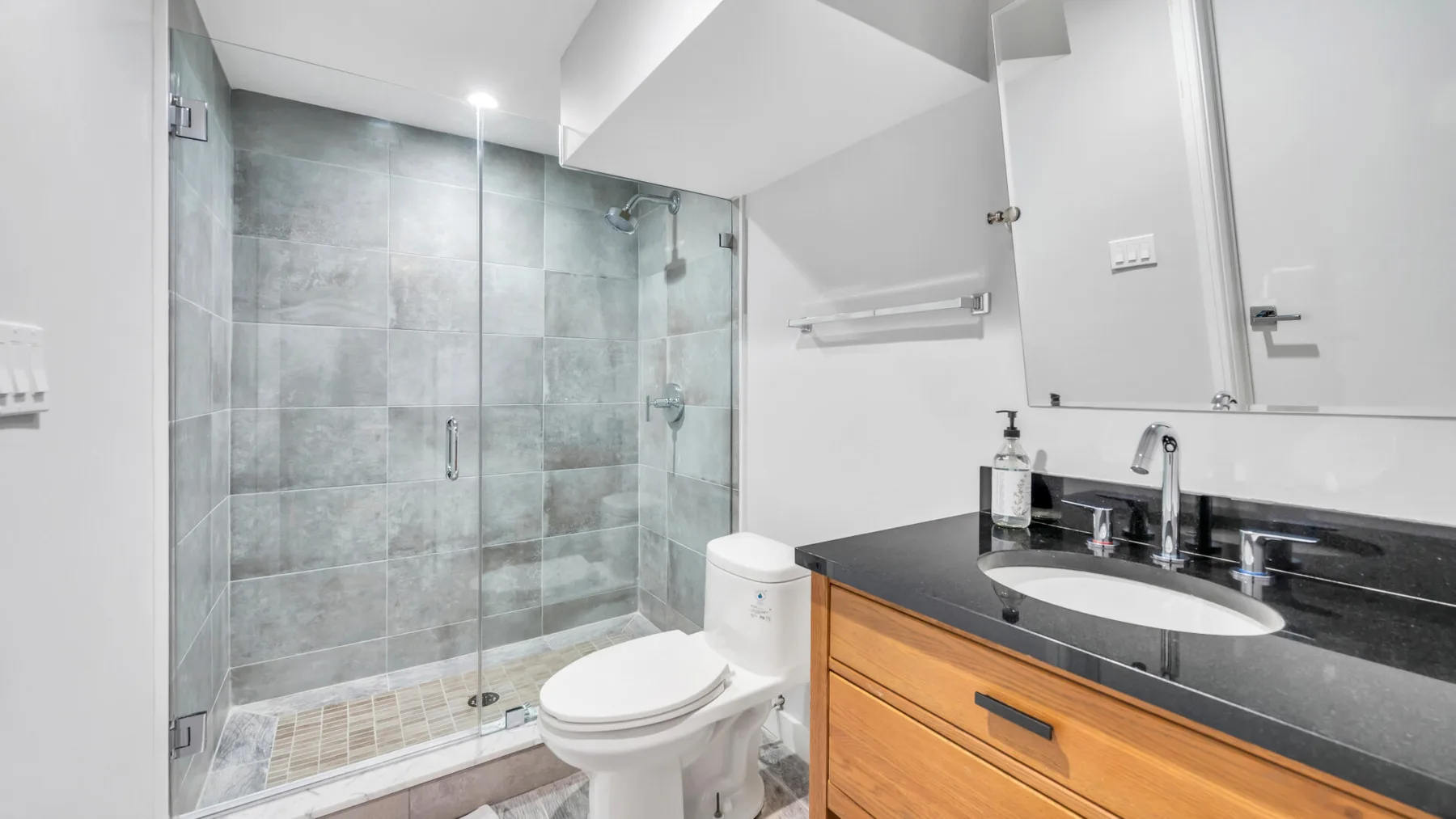 A modern bathroom with a glass-enclosed shower and a vanity.