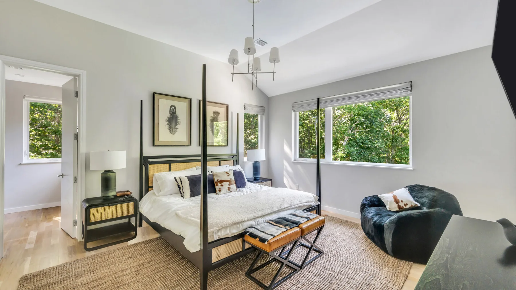 A bright bedroom with a four-poster bed and large windows.