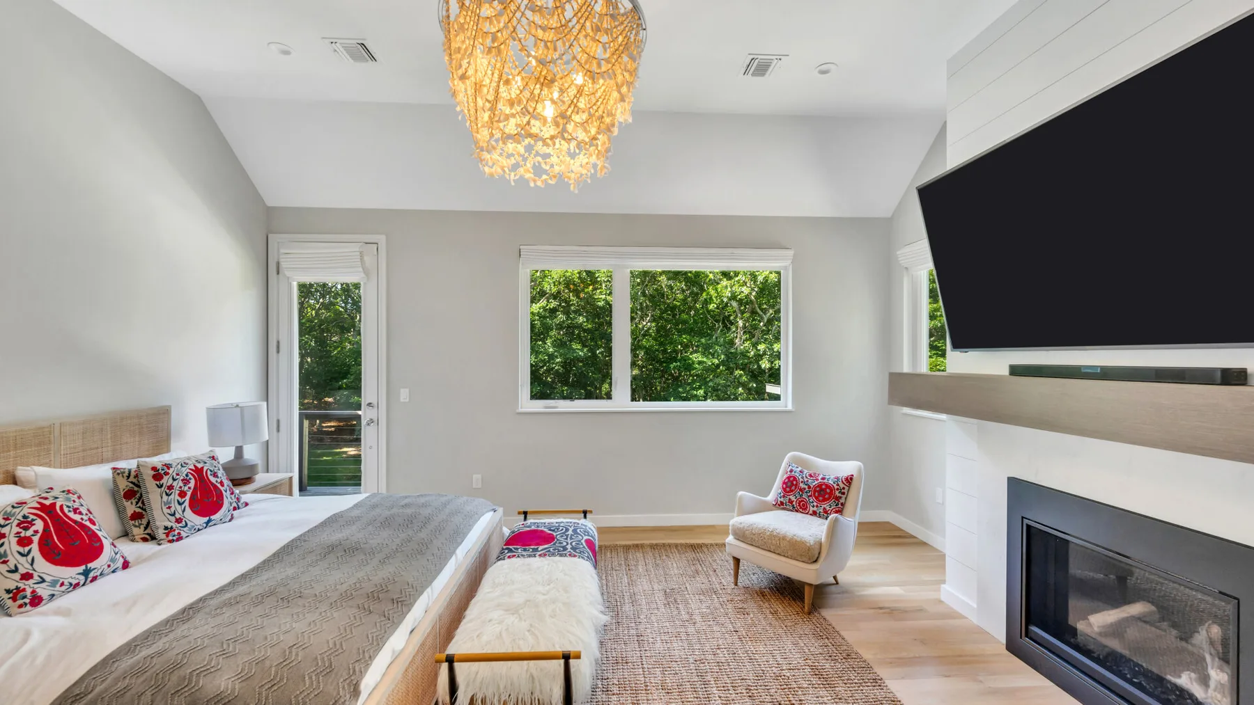 A bright bedroom with a bed, a window, and a fireplace.