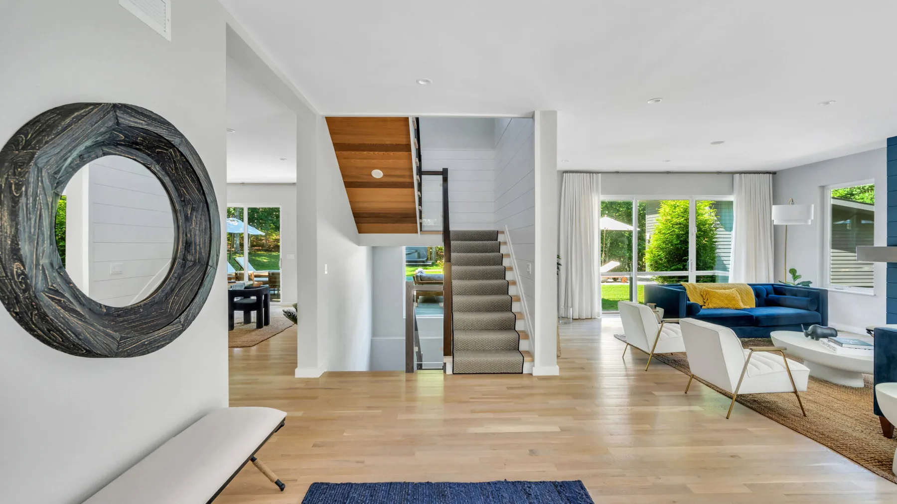 Una luminosa sala de estar de concepto abierto con una escalera y una zona de asientos.