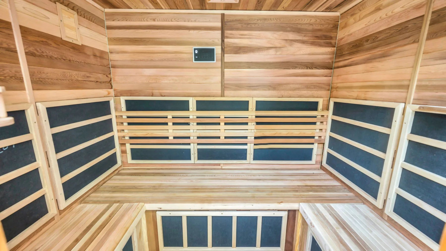 A wood-paneled sauna room with tiered benches and dark inset panels.