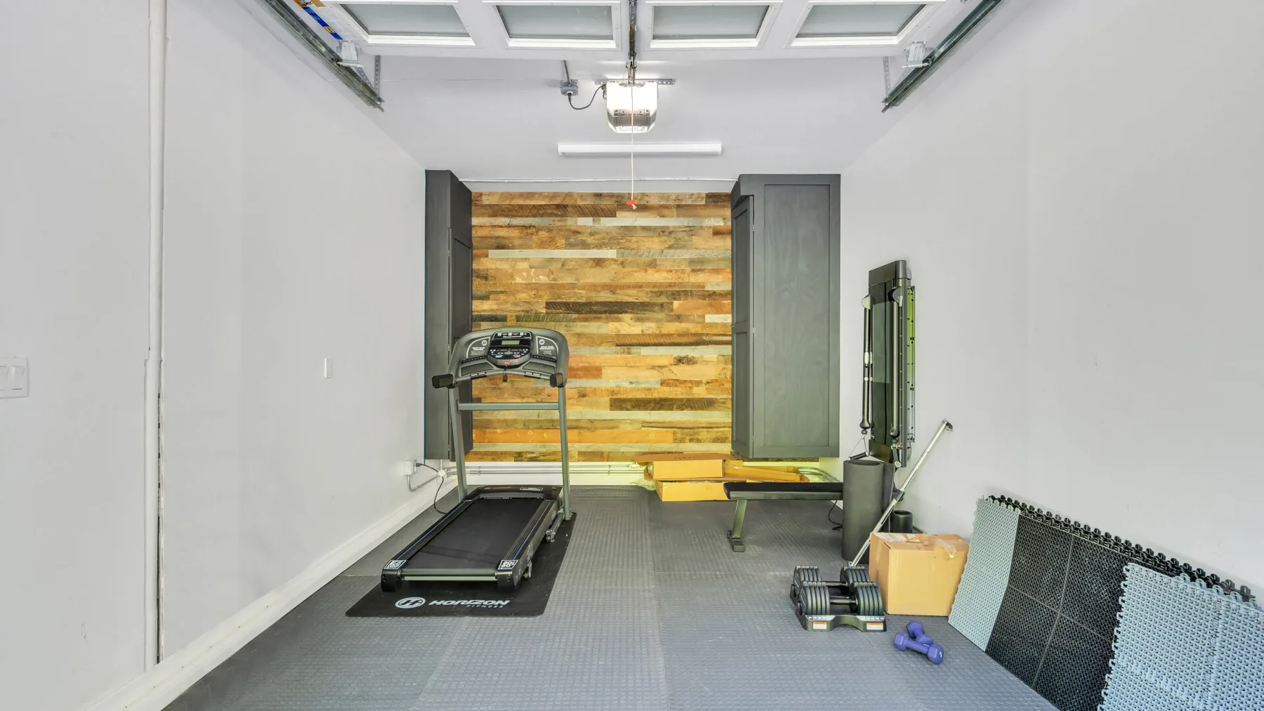 A home gym with a treadmill and exercise equipment.
