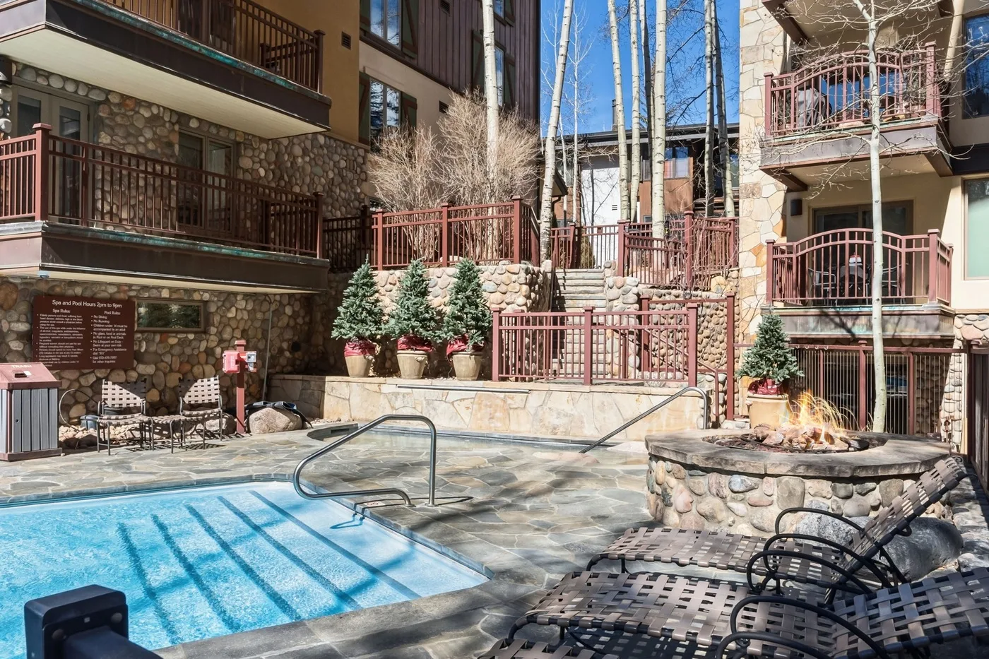Patio con piscina al aire libre, asientos y edificios con fachadas de piedra.