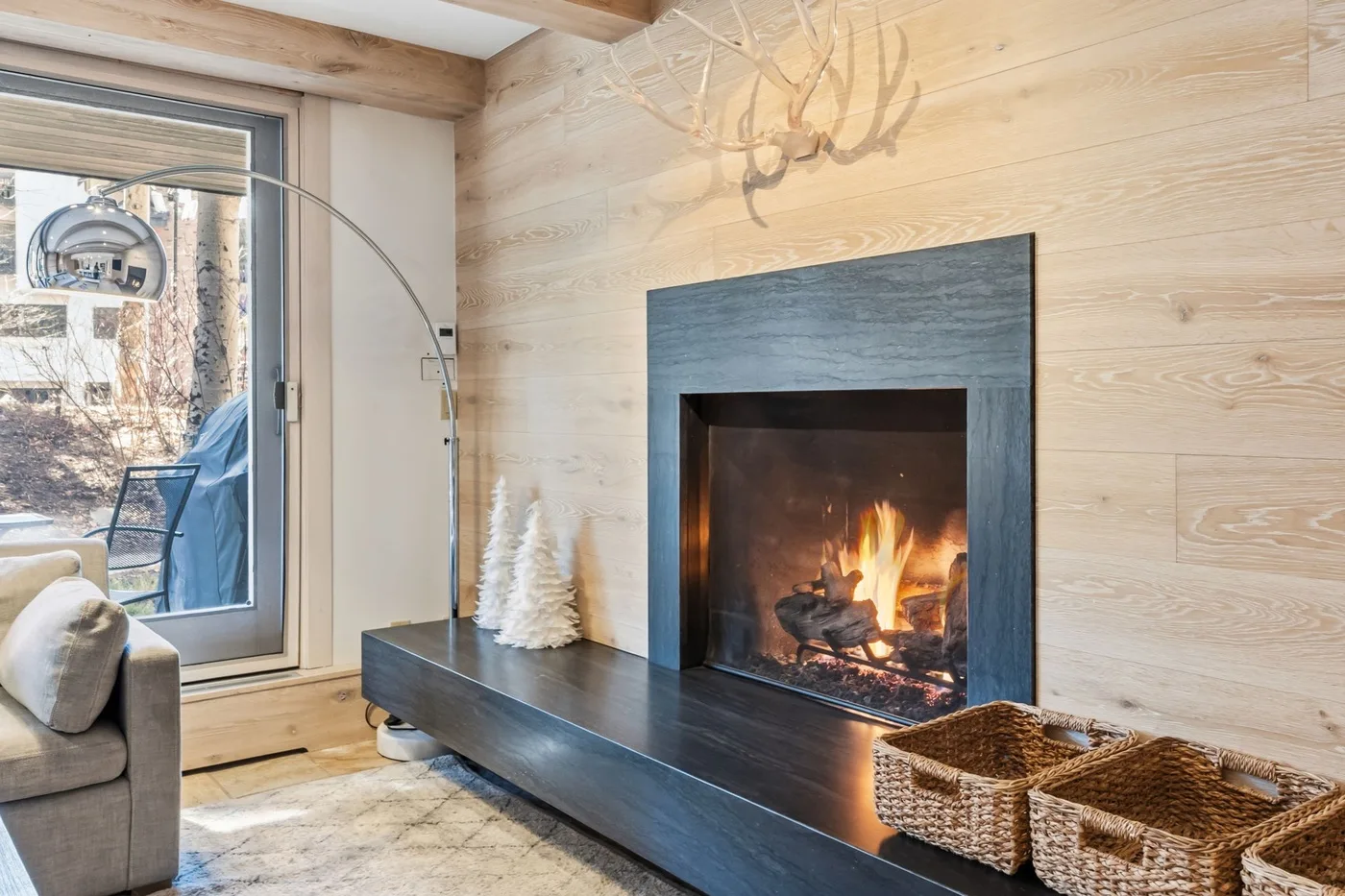 Una sala de estar con chimenea y asientos junto a una ventana grande.