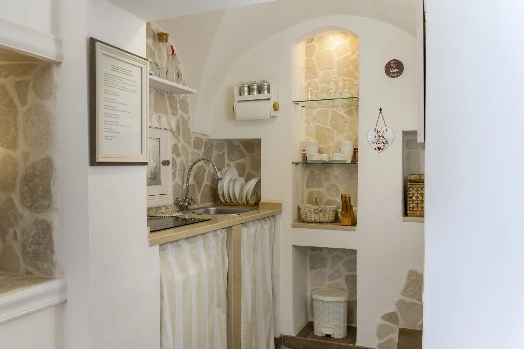 A small kitchenette with a sink and dish rack sits beside recessed display shelves.