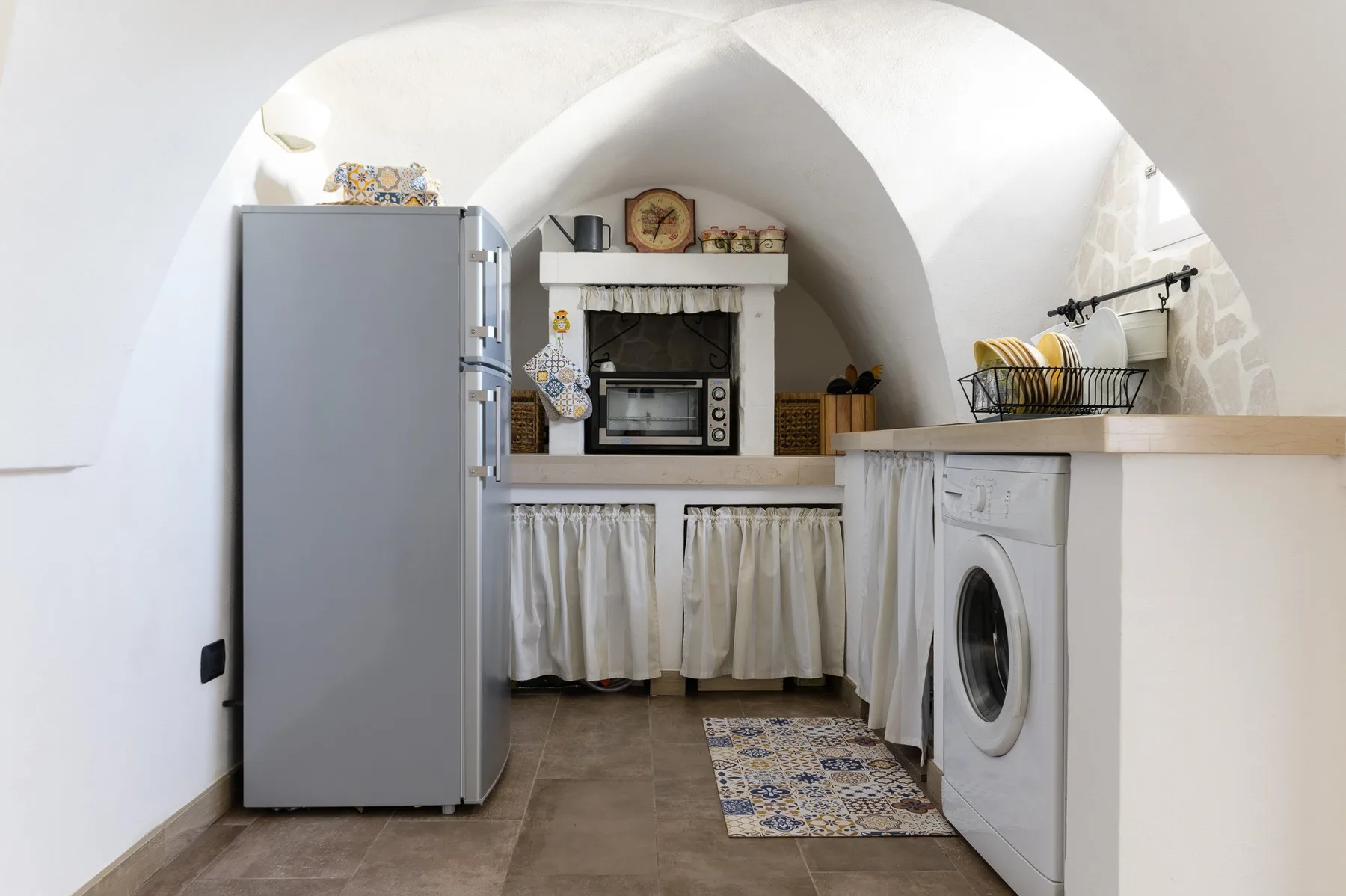 A compact kitchen with a refrigerator, microwave, and washing machine.