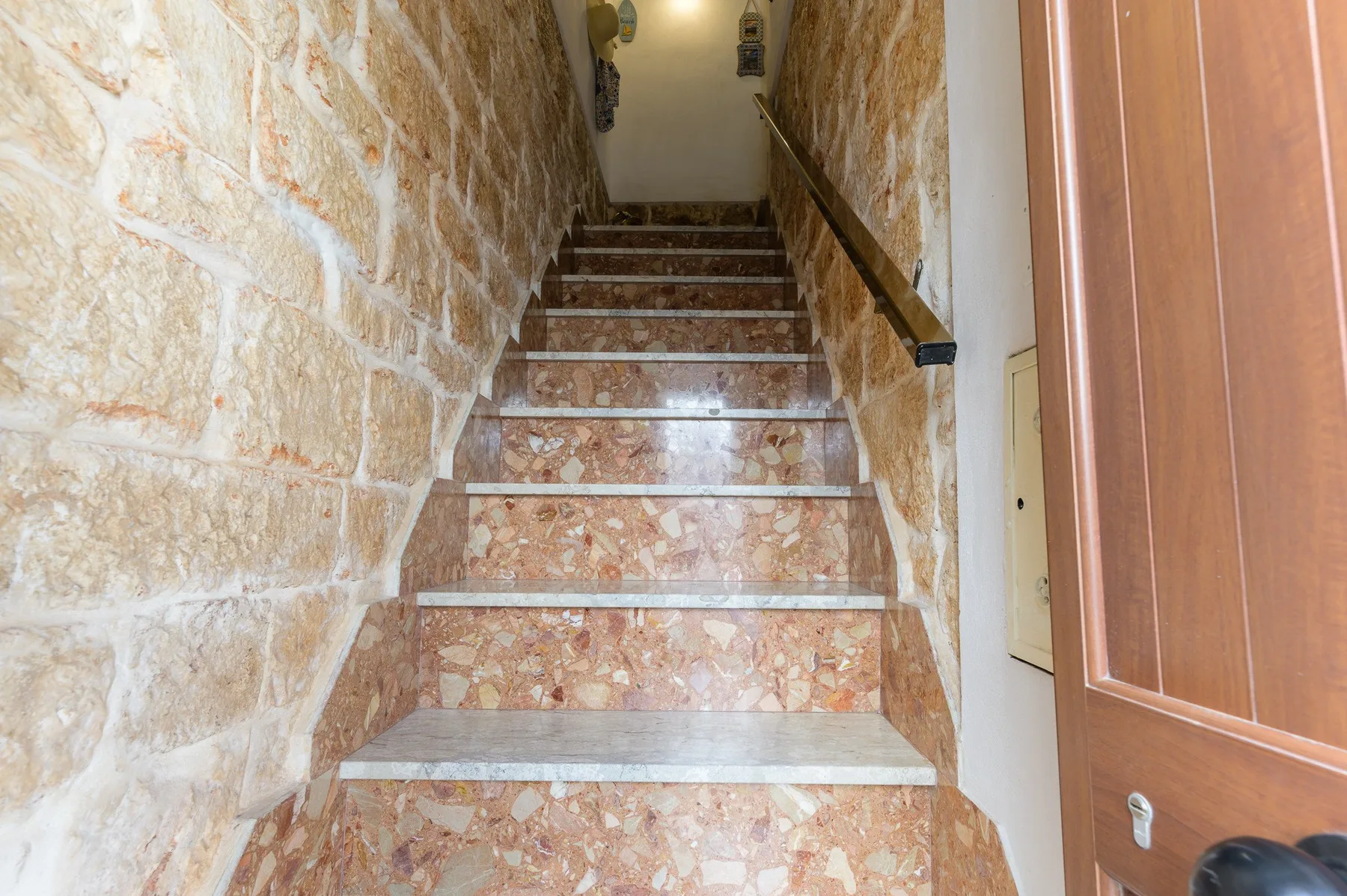 A stone staircase with a dark handrail leads to an upper landing.