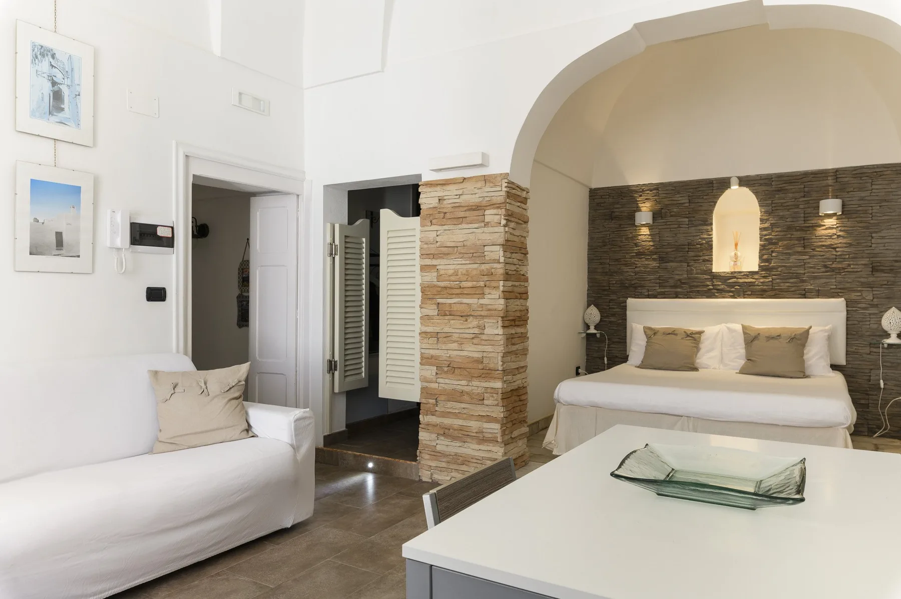 A bright bedroom with a bed, a seating area, and a low table.