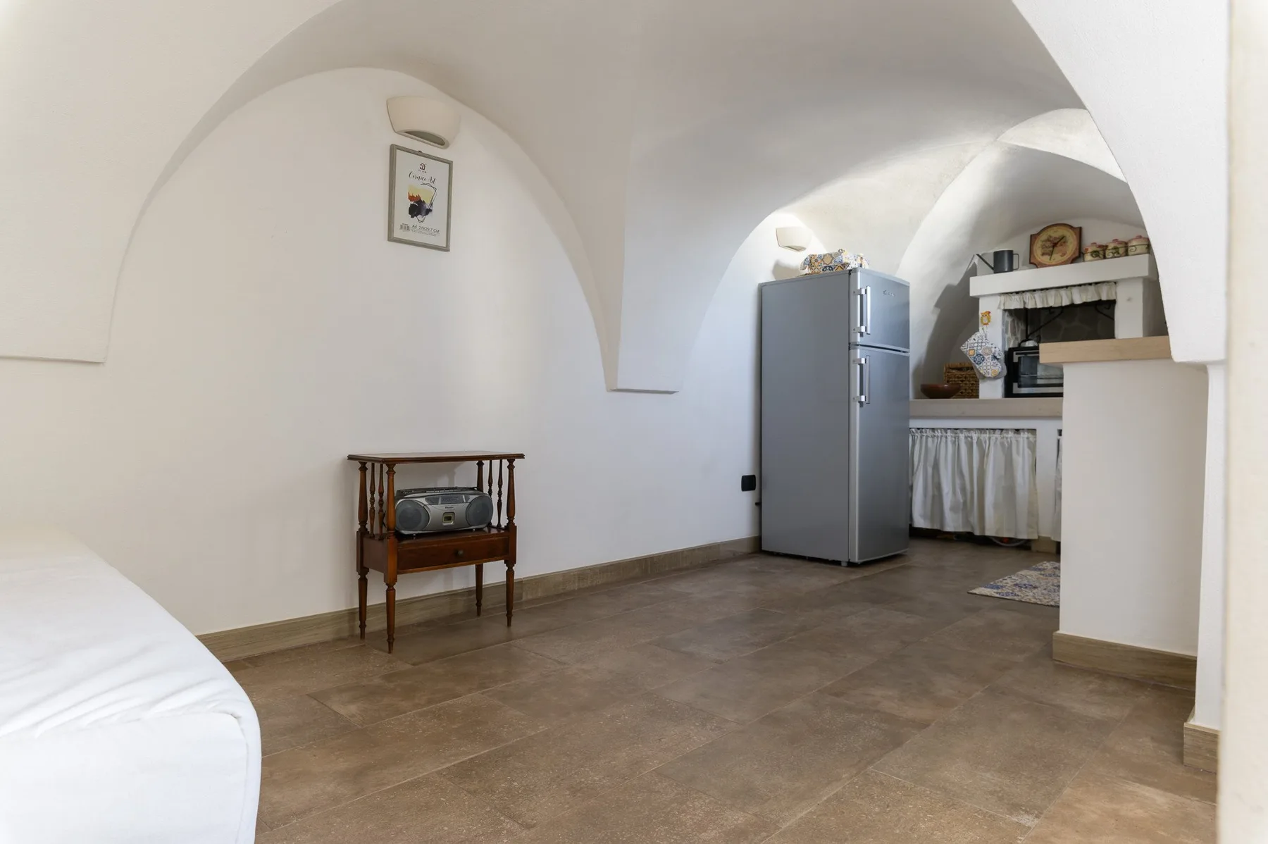 A vaulted room with a refrigerator and a small wooden table.