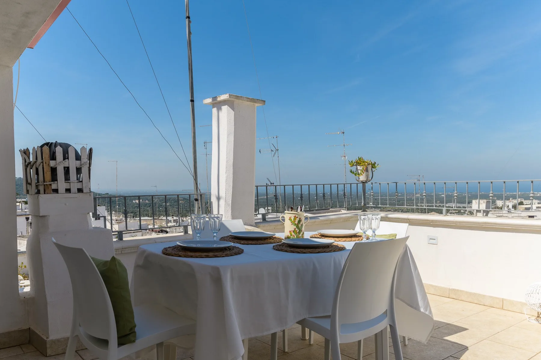 A rooftop dining area with a set table overlooking the surrounding city.