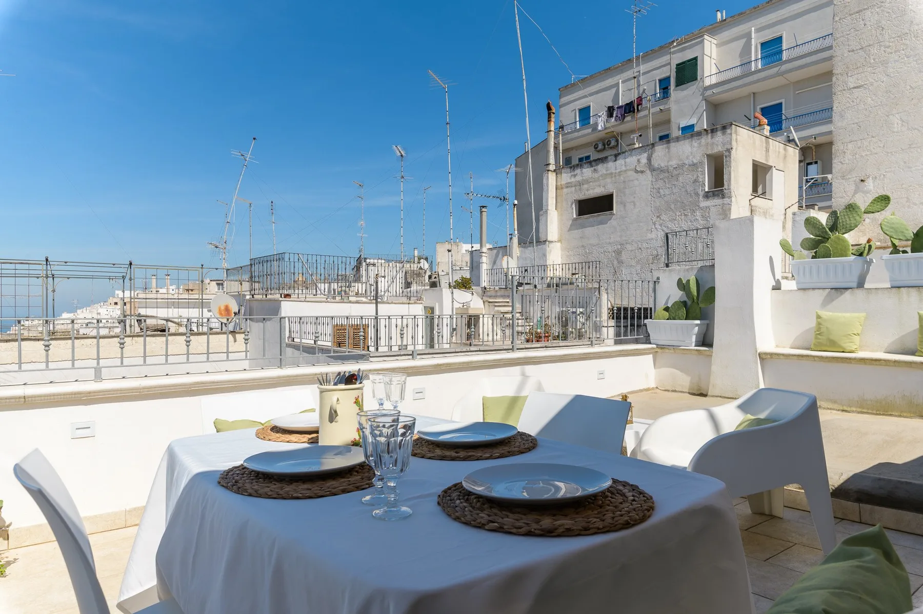 A rooftop dining area with a table set beside the terrace railing.