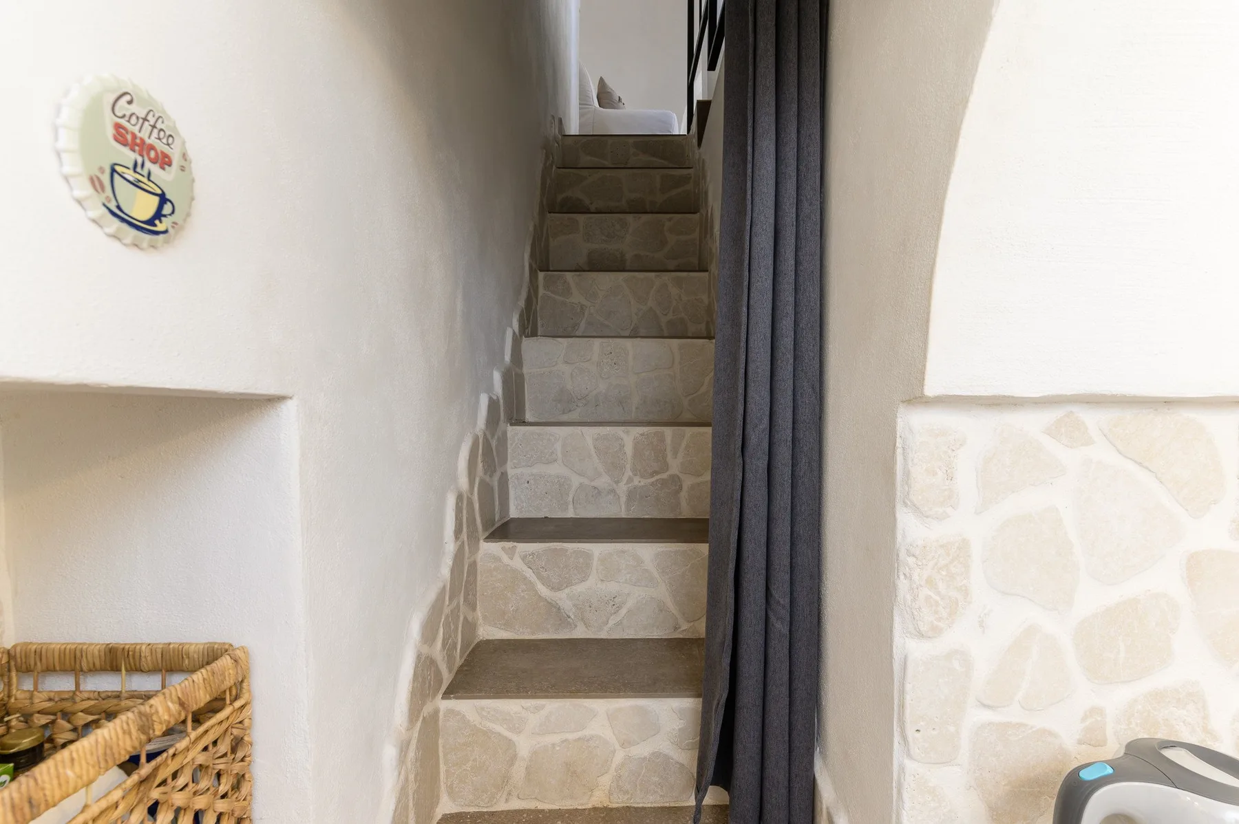 A narrow indoor stone staircase rises beside a dark curtain.
