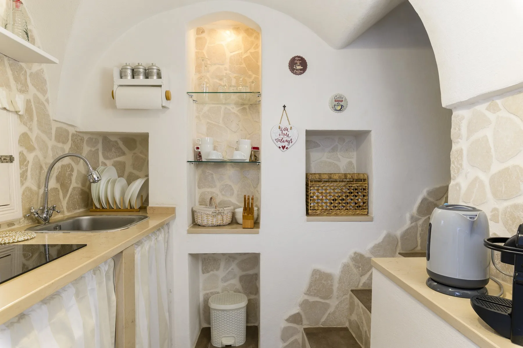 A compact kitchen with a sink, counter, and built-in display niches.