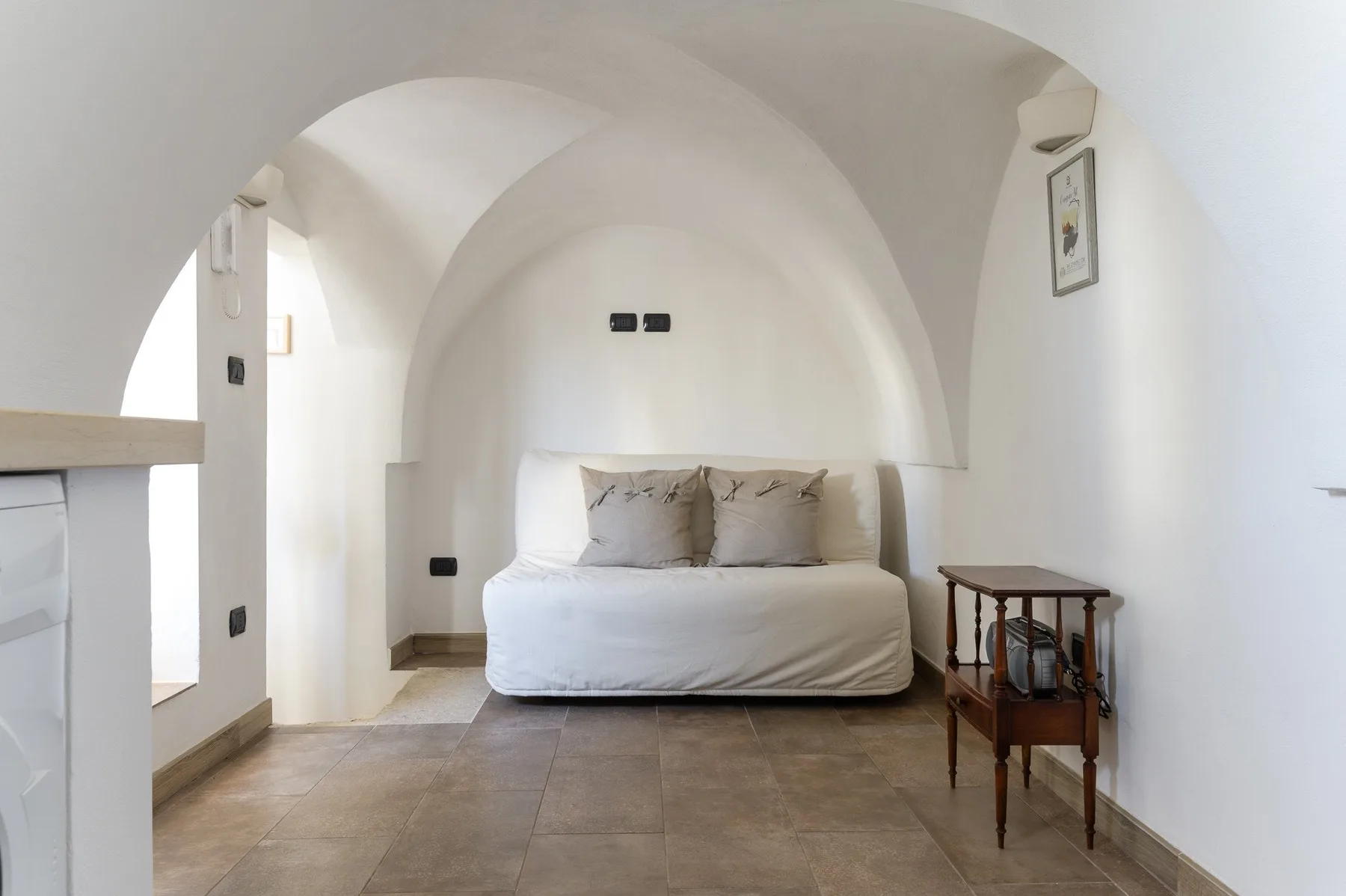 A bedroom with a bed beneath a curved white arch.