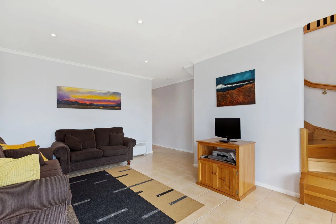 A living room with seating, a television, and wall art.