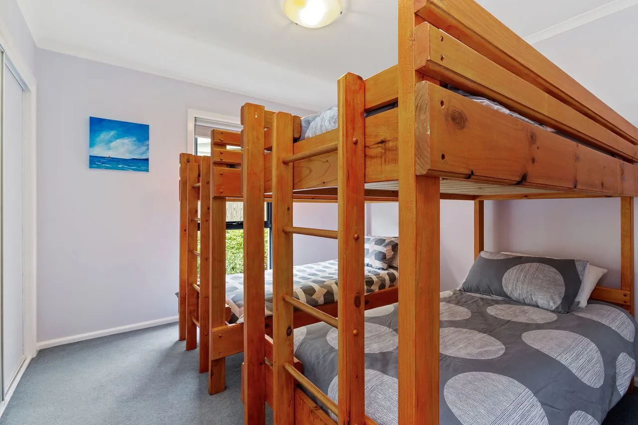 A bedroom with wooden bunk beds and patterned bedding.