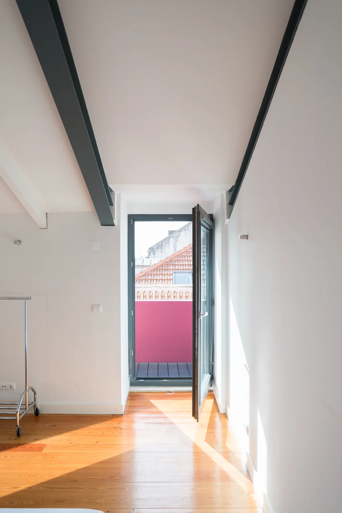 Una habitación luminosa da a un pequeño balcón a través de una puerta de vidrio.