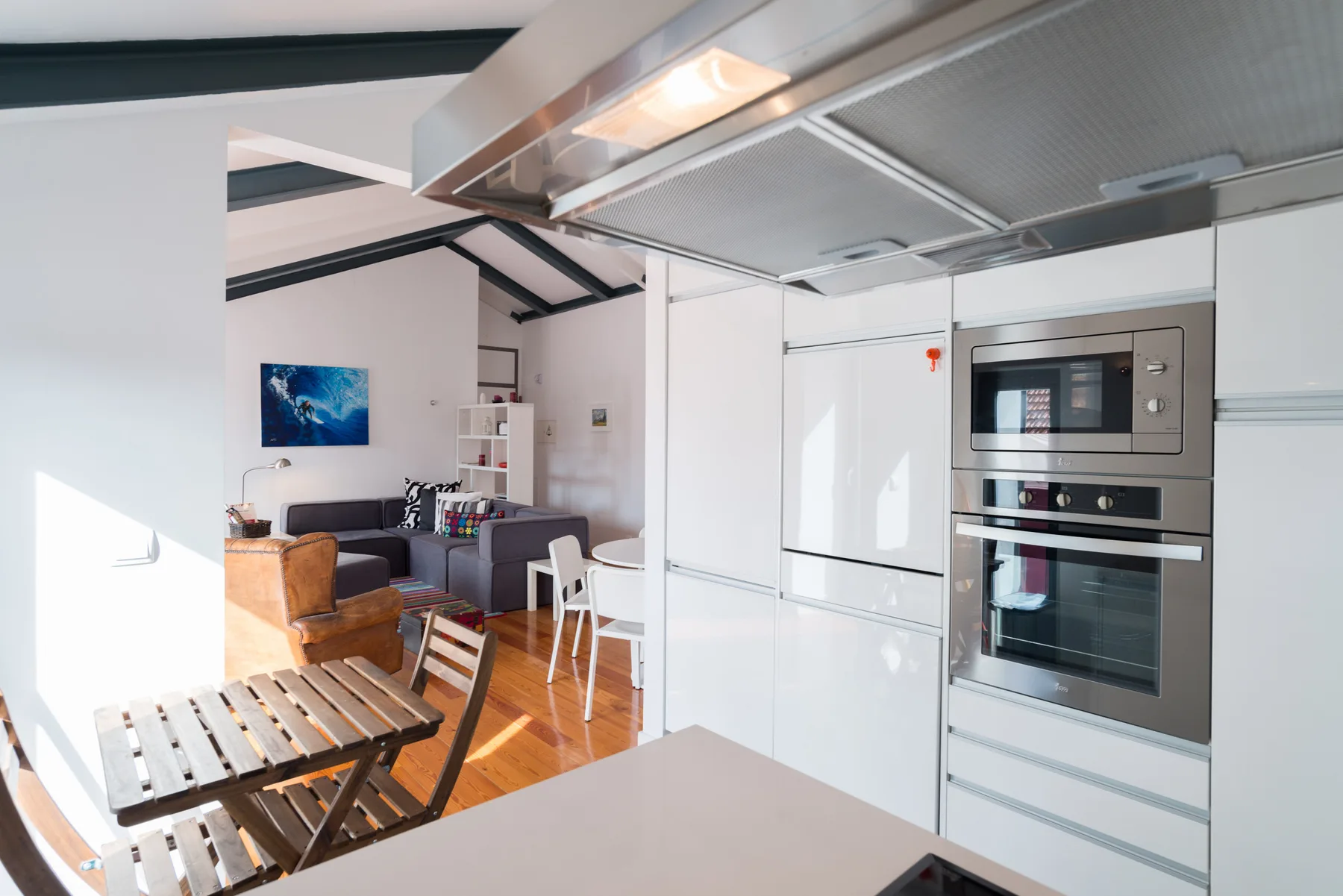 Cocina y sala de estar de concepto abierto con muebles blancos y una mesa de comedor.