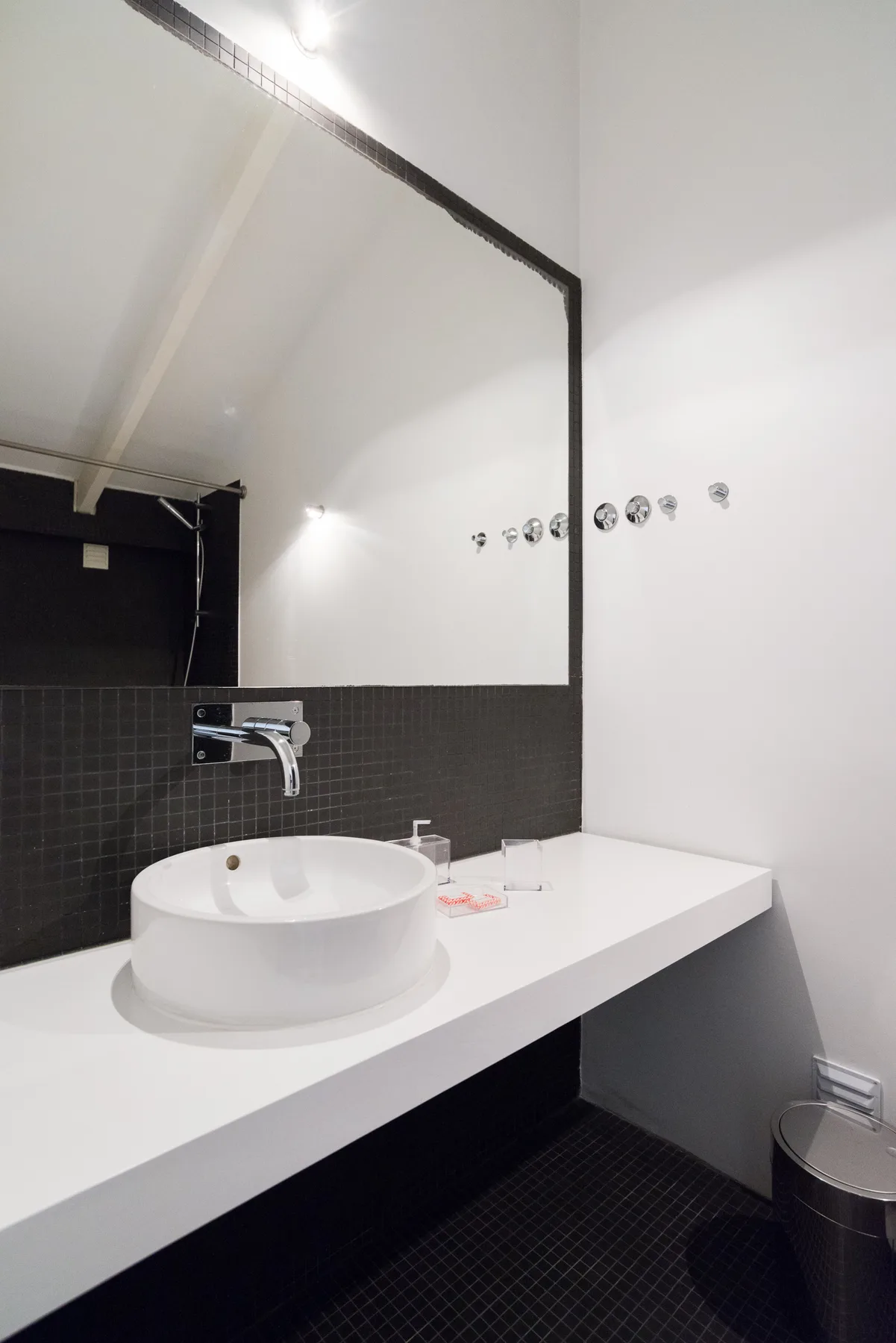 Un baño moderno con lavabo sobre encimera blanco y un espejo grande.