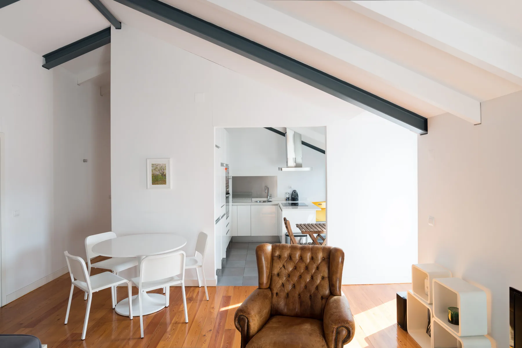 Una luminosa sala de estar diáfana con mesa de comedor y cocina al fondo.