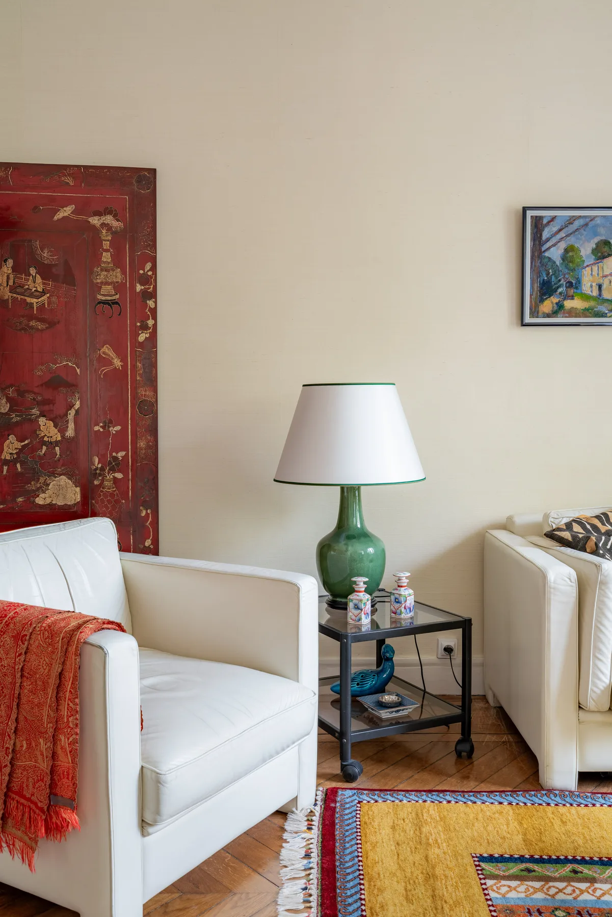 Una zona de estar con asientos blancos, una lámpara y textiles coloridos.