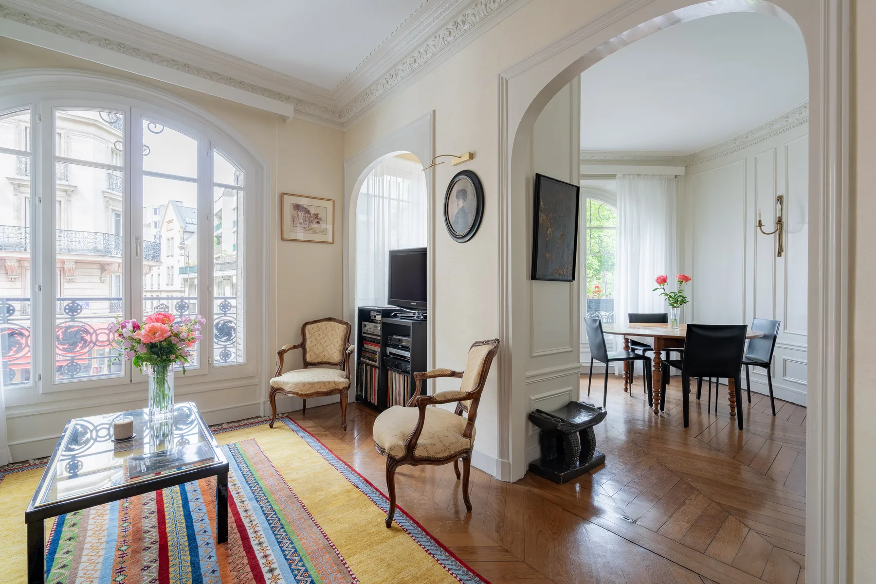 Una sala luminosa con asientos, ventanas amplias y vista a un comedor.