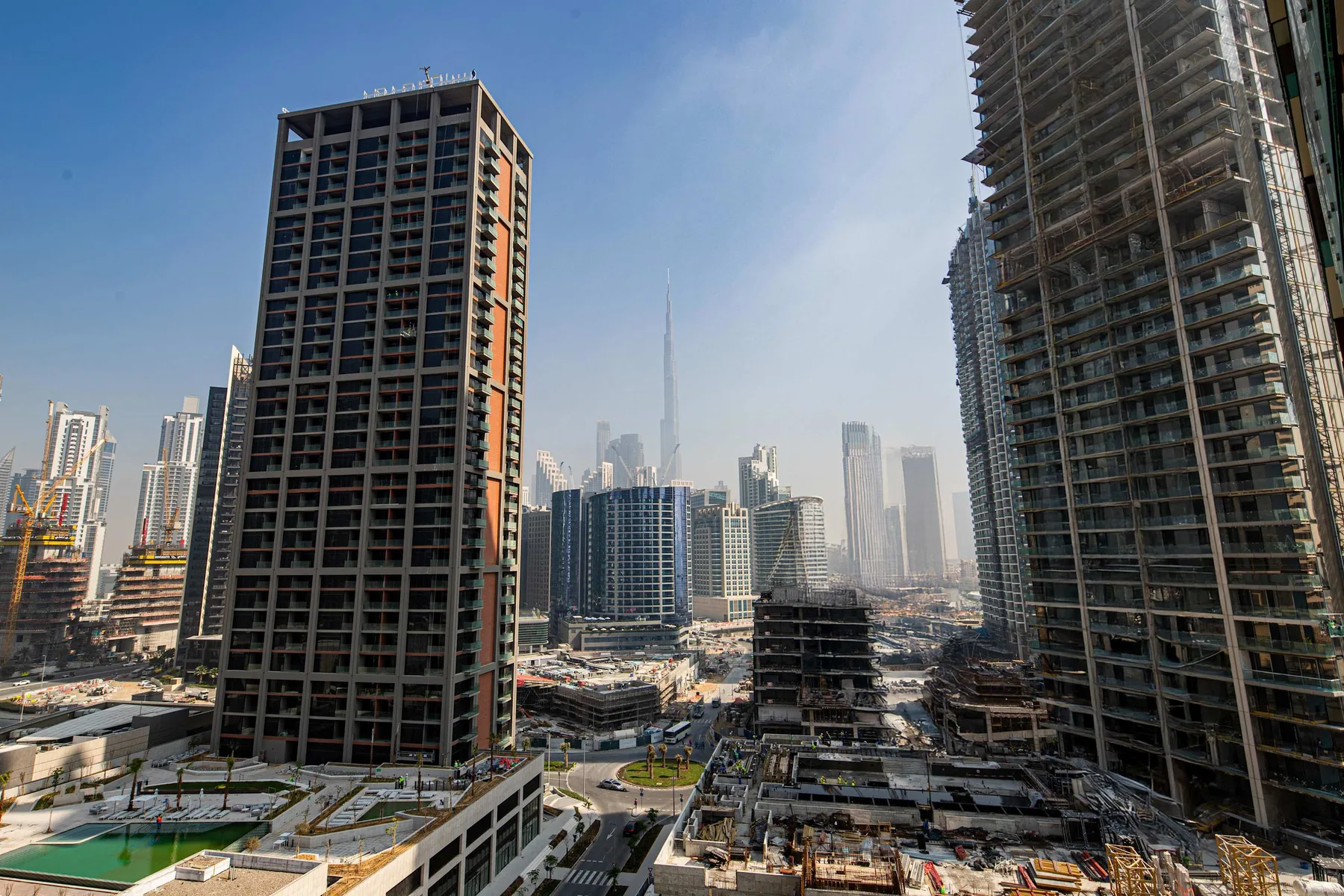 Un horizonte urbano con edificios altos y obras de construcción bajo un cielo despejado.