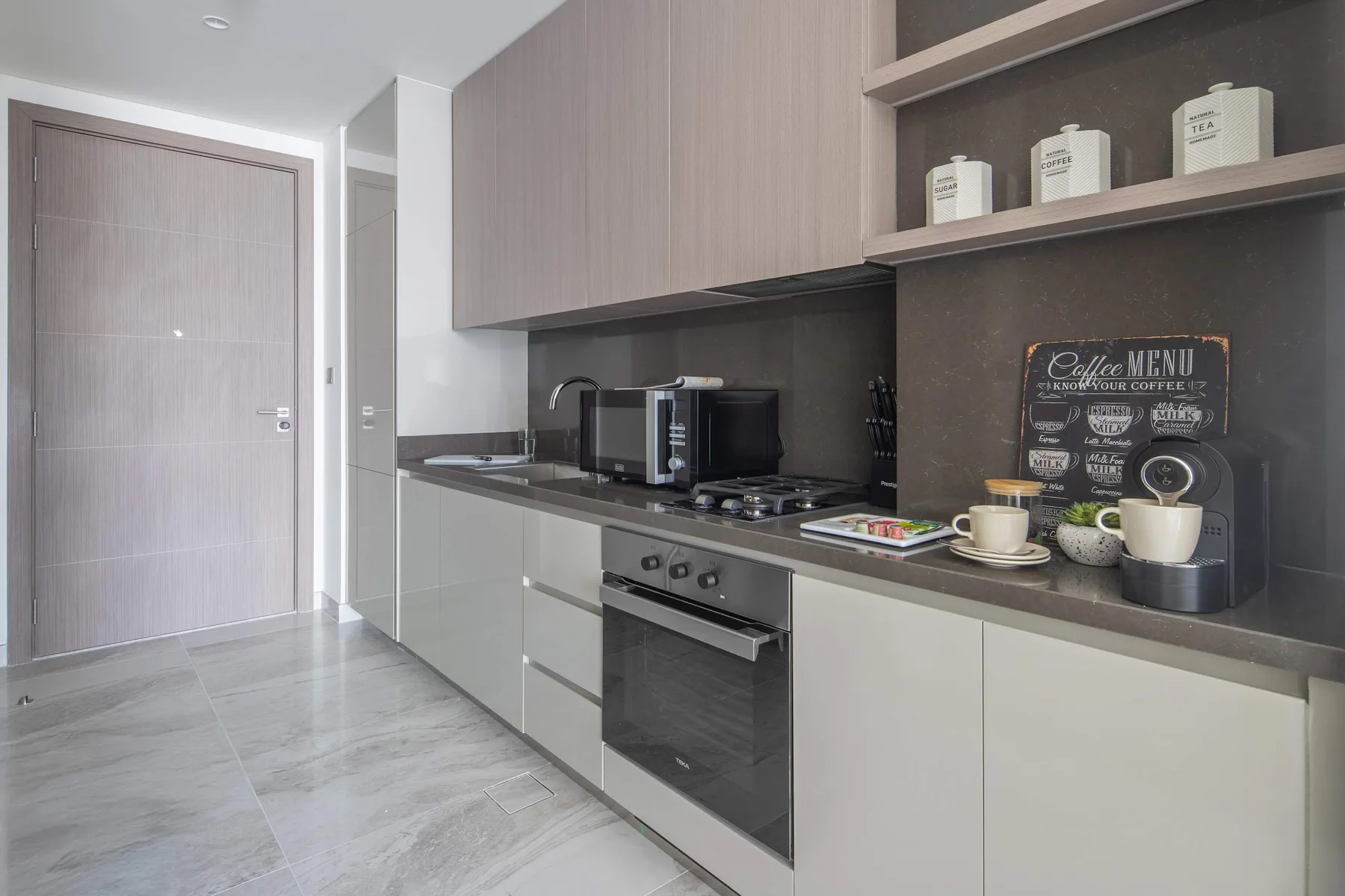 Una cocina moderna con horno empotrado y pequeños electrodomésticos sobre la encimera.