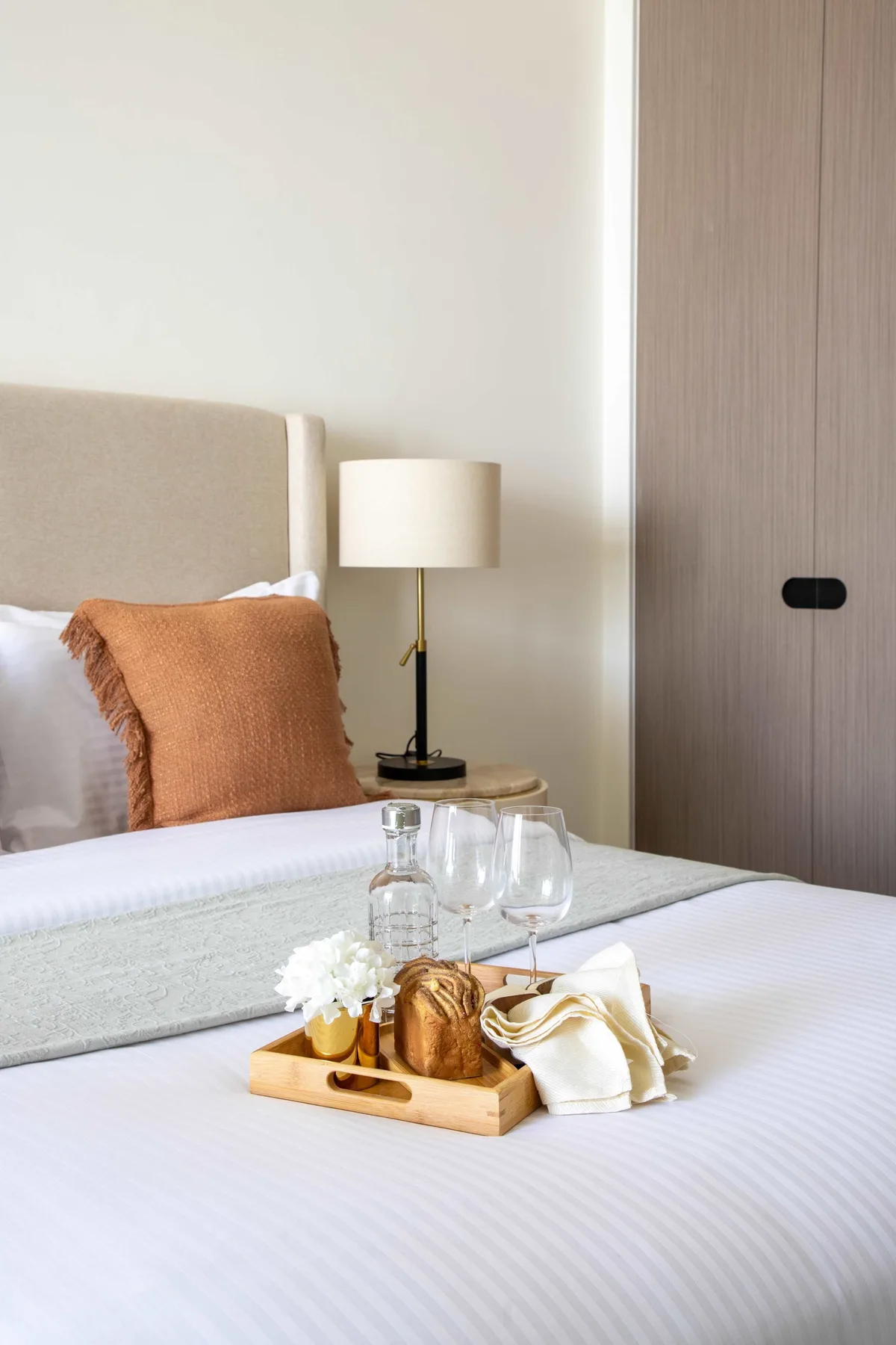 Un dormitorio con la cama tendida y una bandeja con bebidas y comida.