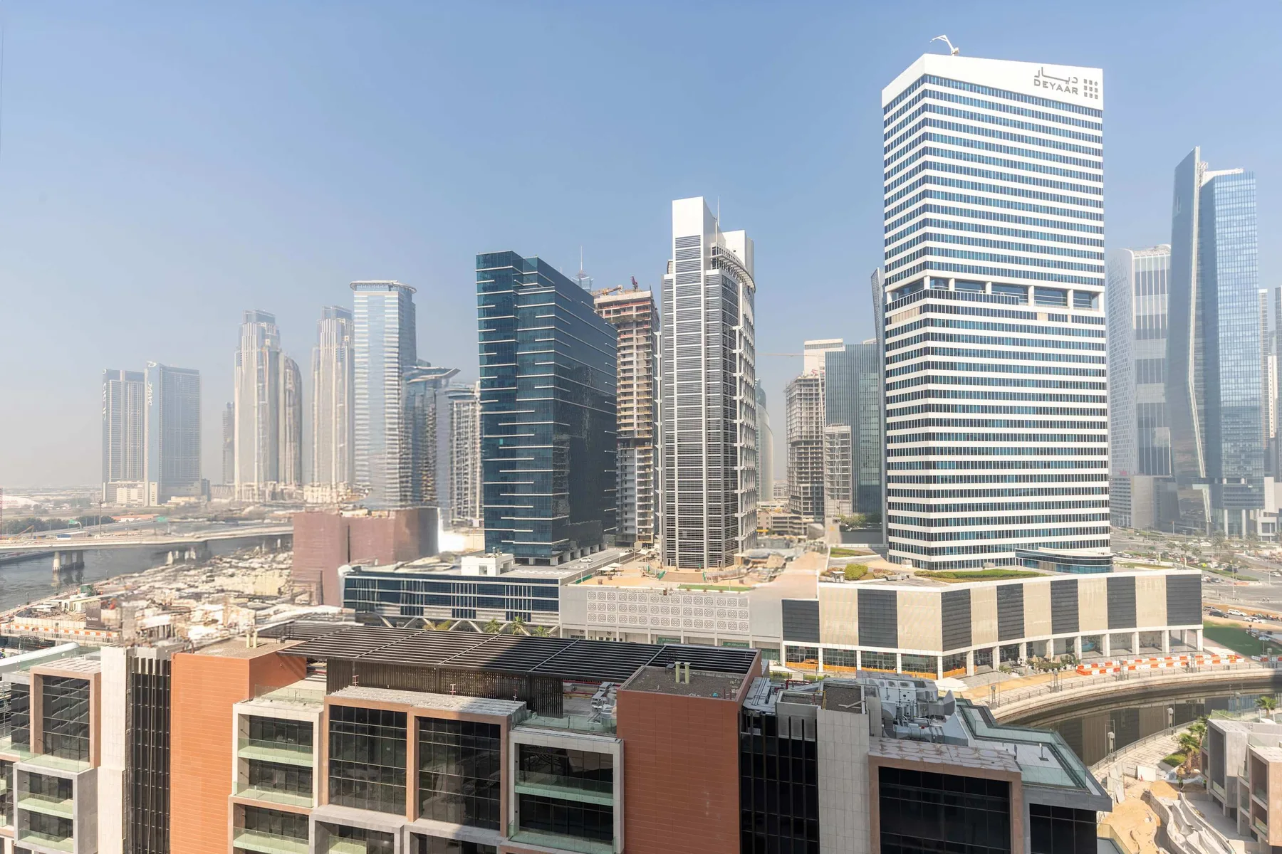 Horizonte urbano con edificios altos modernos y un gran complejo comercial en primer plano.
