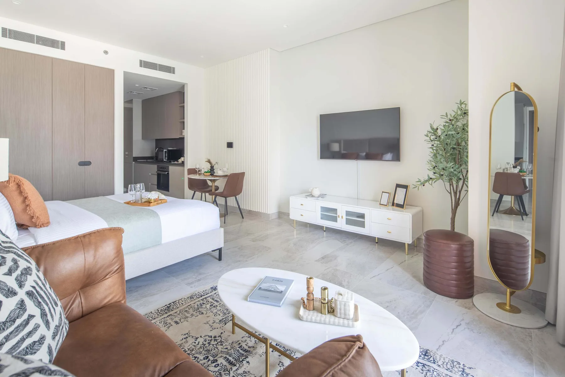 Un dormitorio luminoso con una cama, un televisor en la pared y una zona de estar.