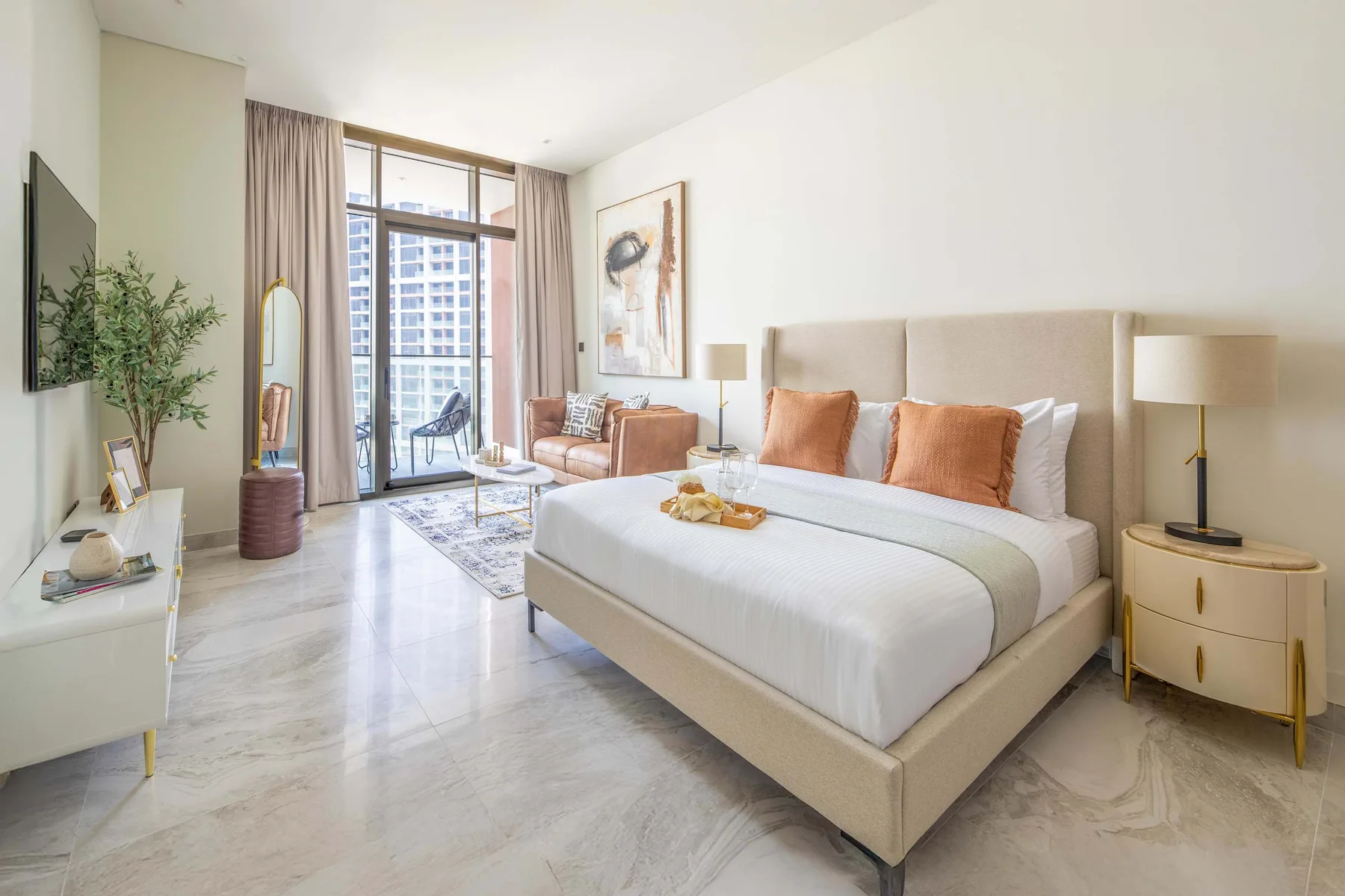 A bright bedroom with a large bed and a seating area by the windows.