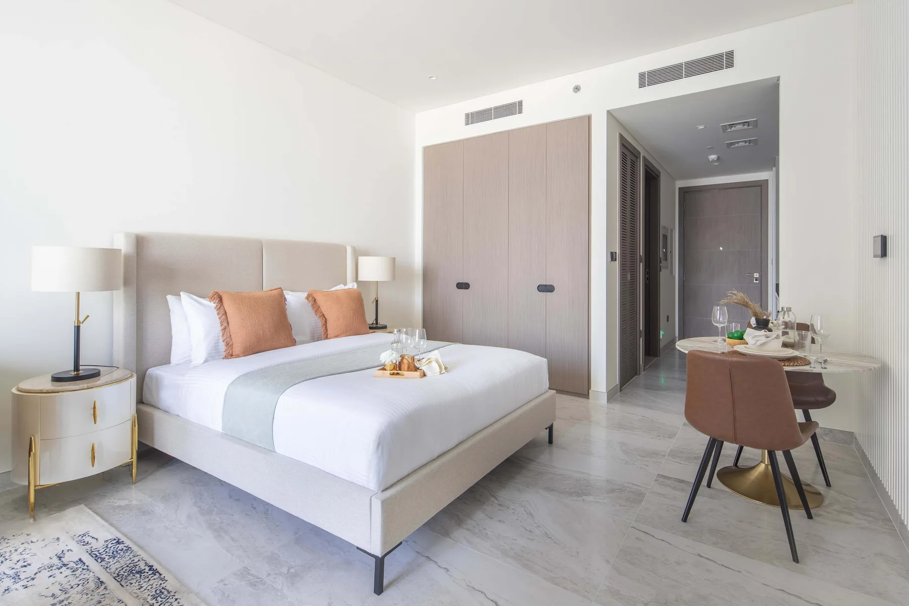 Un dormitorio luminoso con una cama bien arreglada y una pequeña zona de comedor.