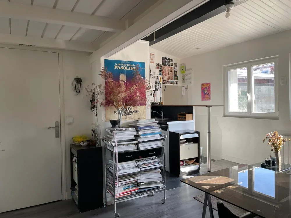 A bright workroom with a desk, shelves of papers, and windows.