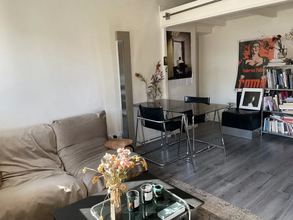 A living room with seating and a dining table beside a bookshelf.