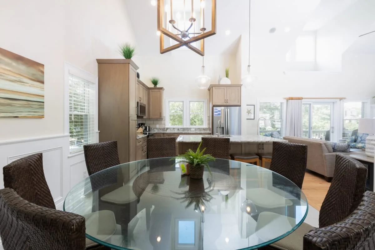 Un comedor y cocina diáfanos y luminosos con una mesa redonda de vidrio.