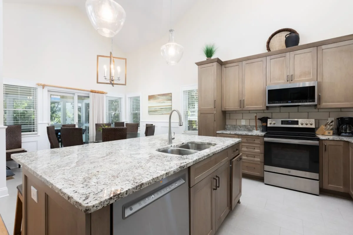Una cocina luminosa cuenta con una isla grande con fregadero y gabinetes alrededor.