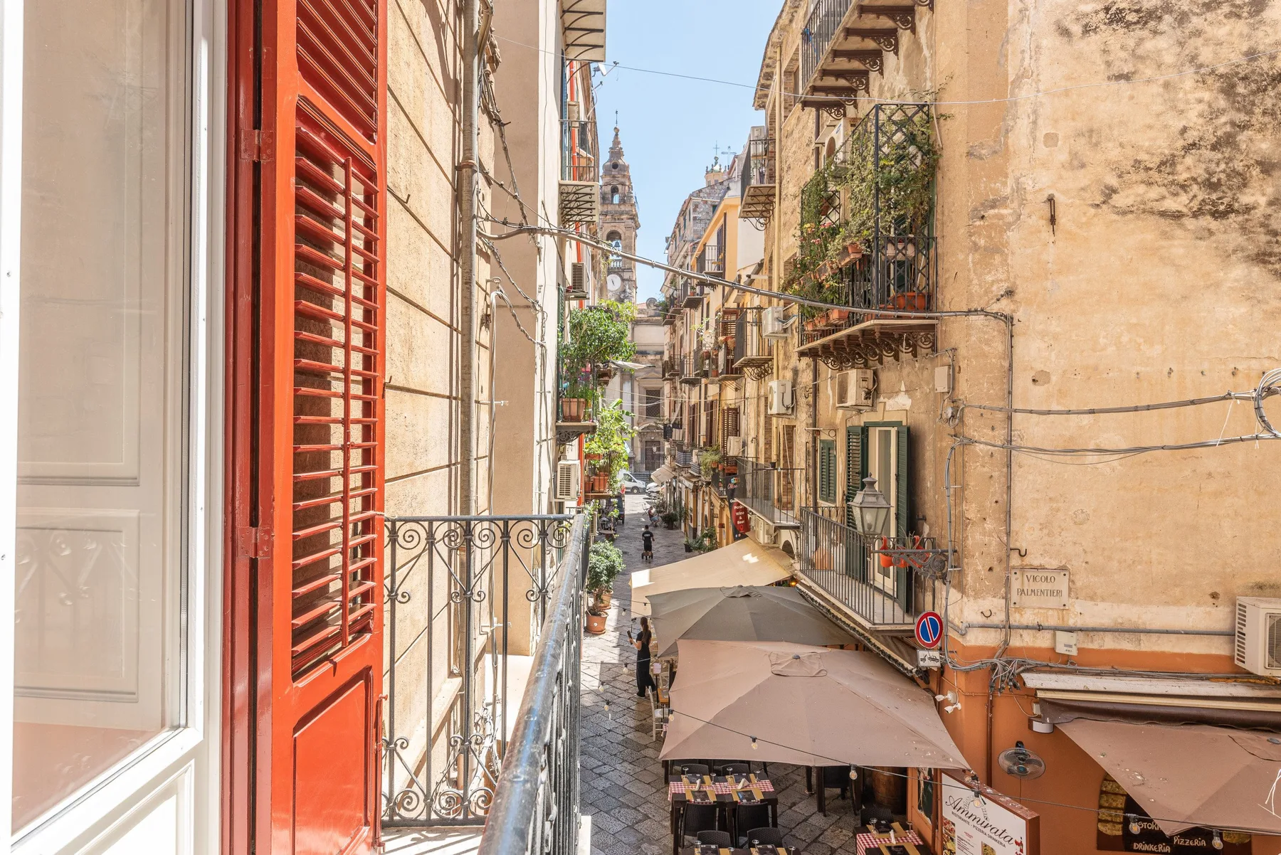 A narrow European street lined with historic buildings and outdoor café seating.