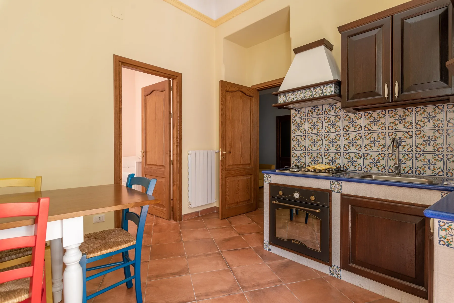 A kitchen with dark wood cabinets, patterned tile backsplash, and a dining table.