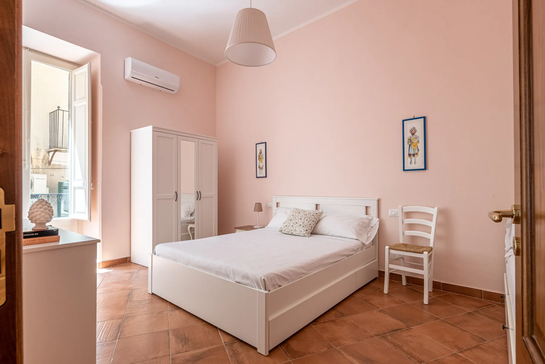 A bedroom with a double bed, wardrobe, and pale pink walls.