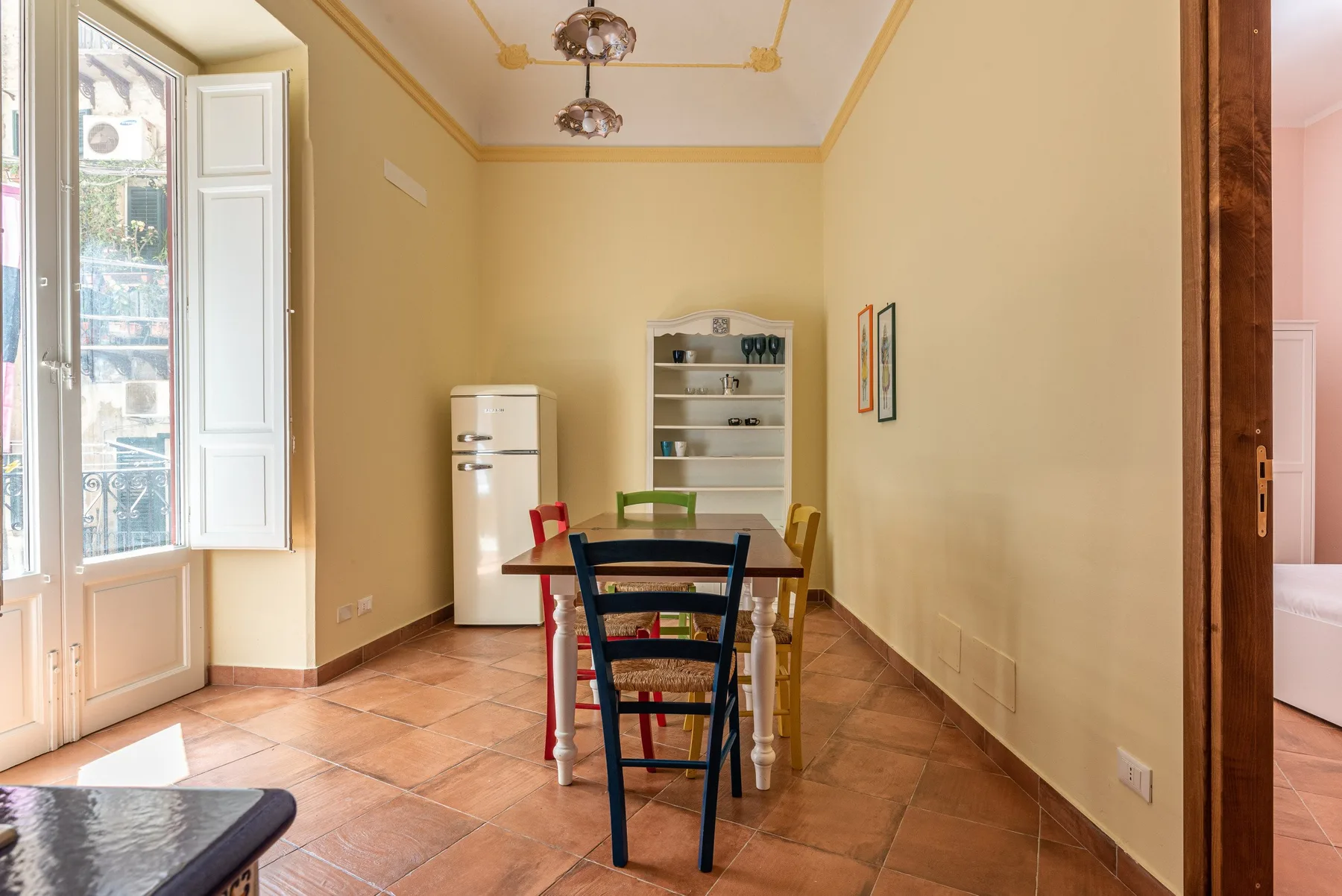 Comedor con una mesa y sillas junto a una ventana abierta.