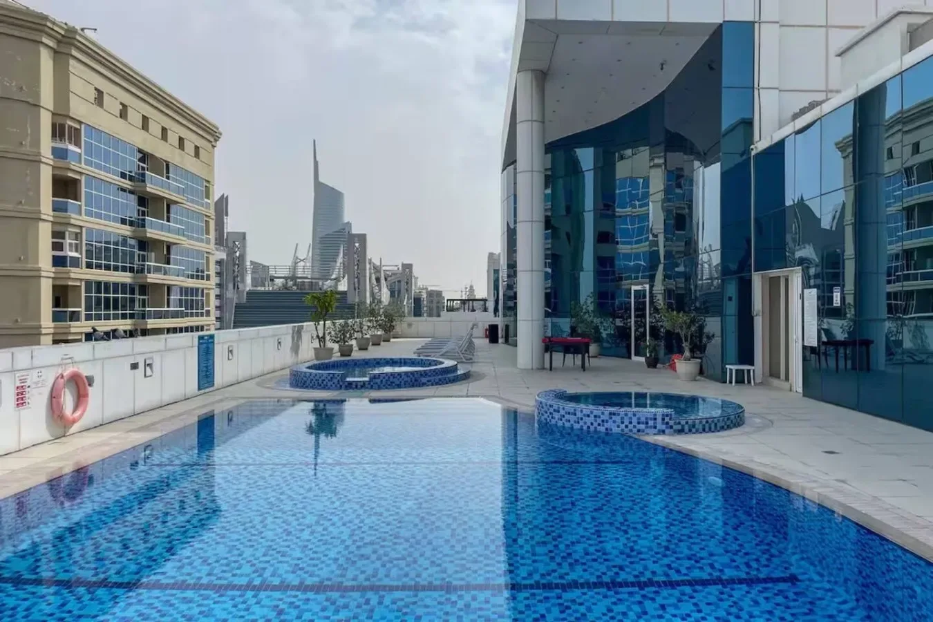 Una piscina en la azotea junto a un edificio moderno con fachada de vidrio.