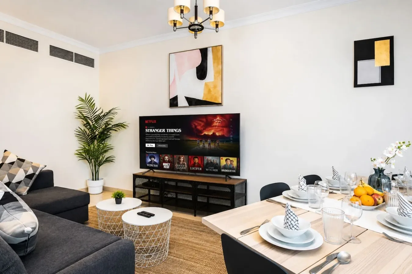 Una luminosa sala de estar y comedor con televisor, asientos y una mesa puesta.
